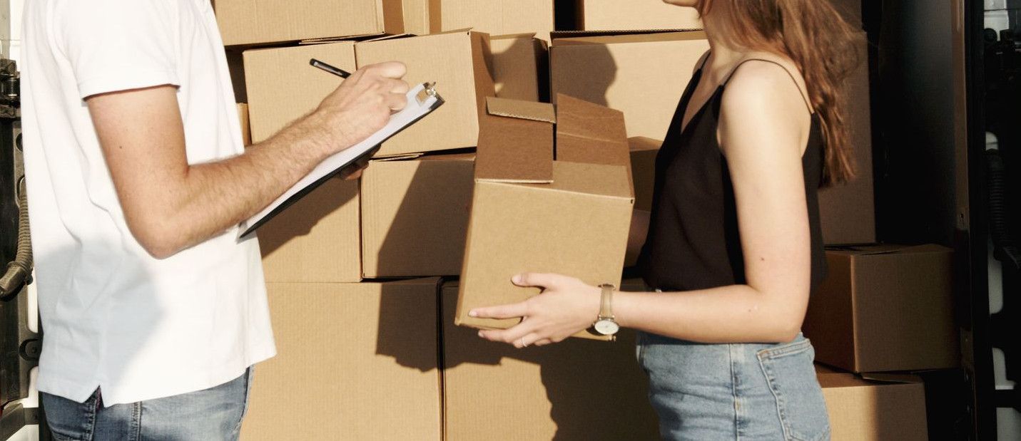 A male and female courier organizing packages in a delivery truck for efficient shipment.